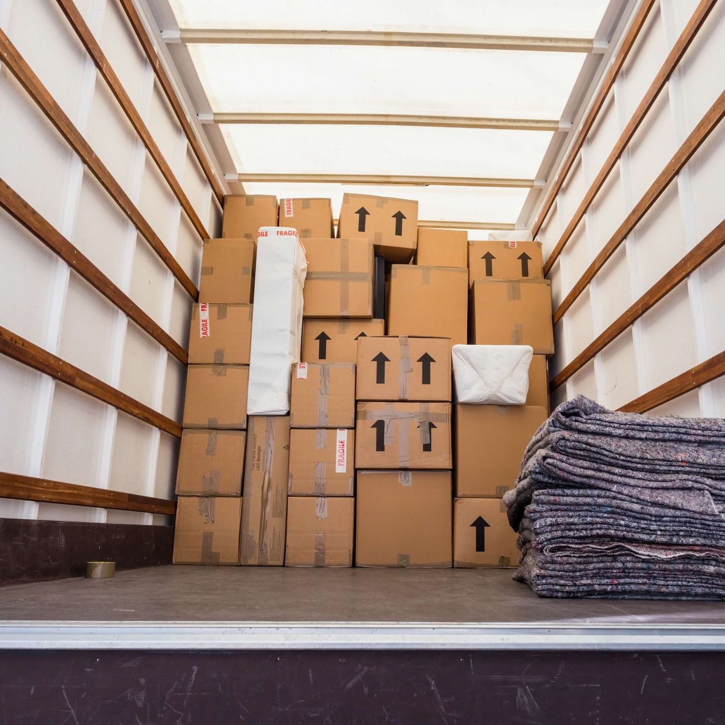 the inside of a moving truck filled with boxes and blankets .