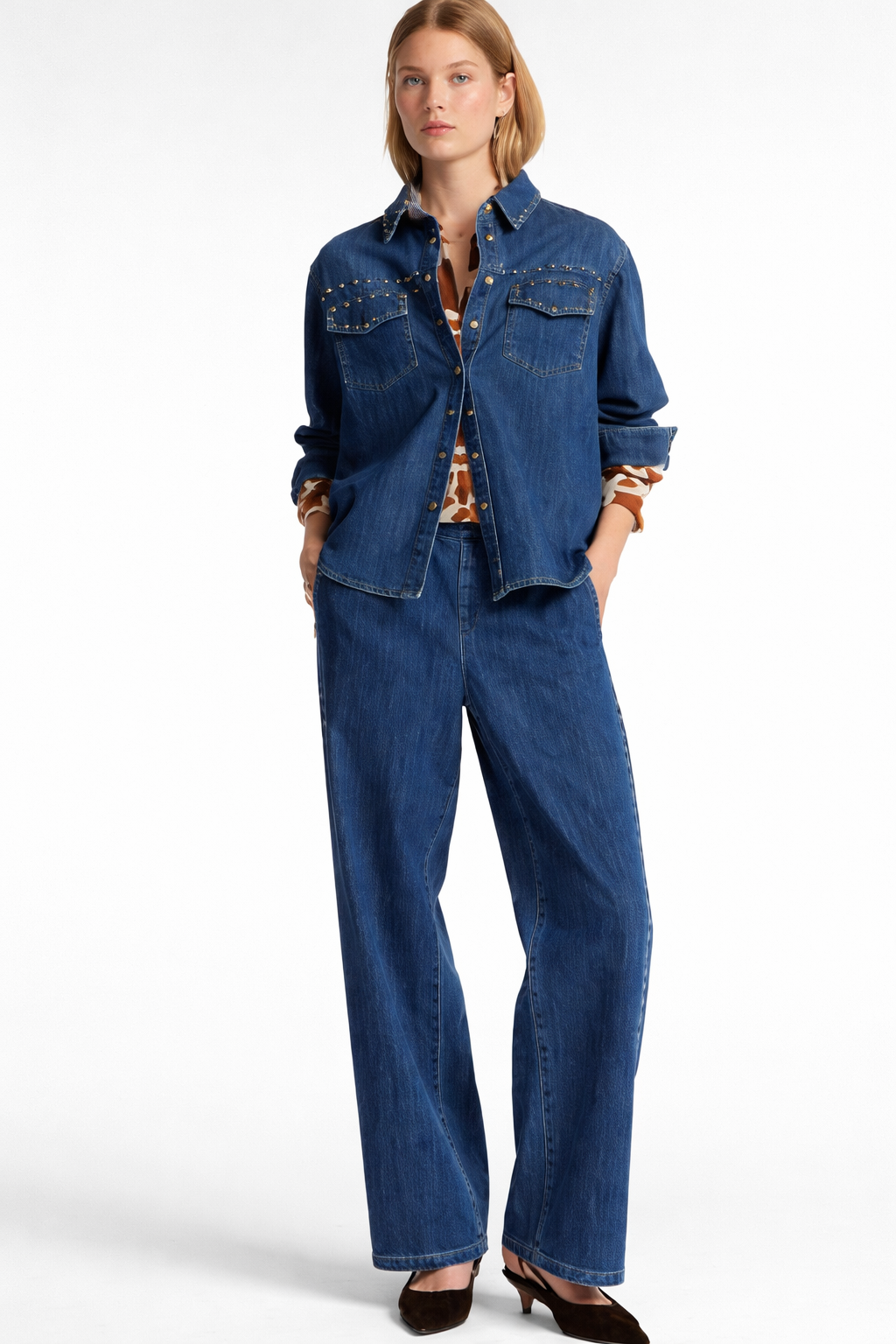 Donna con camicia e pantaloni di jeans, mani in tasca.