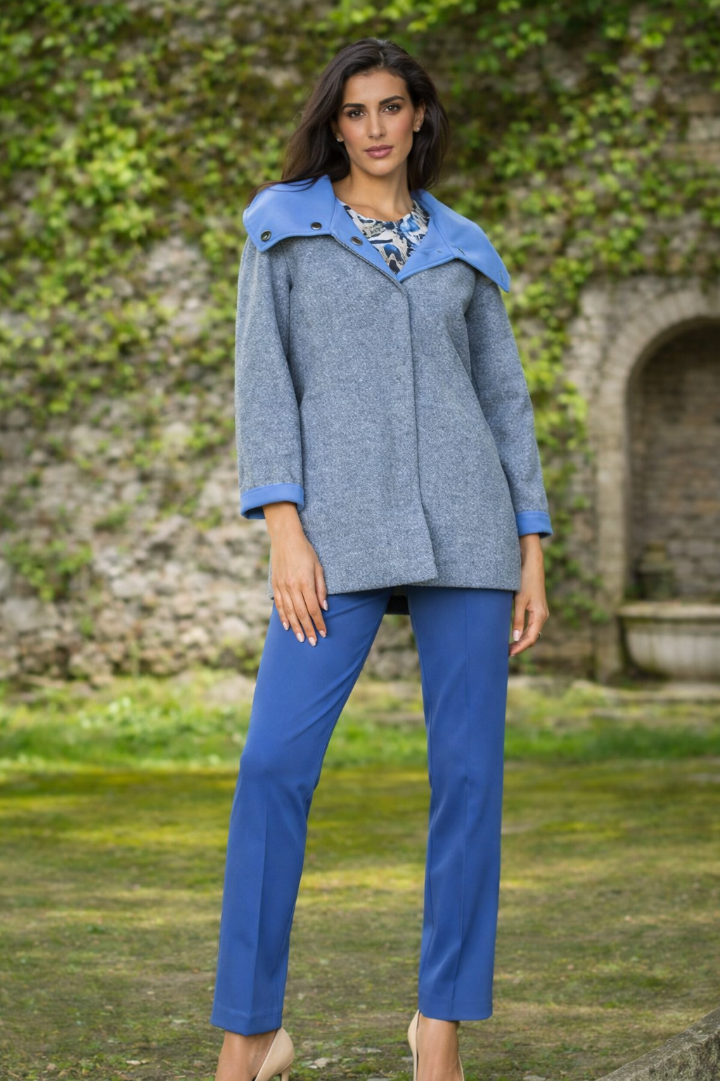 Donna in cappotto blu e pantaloni in piedi all'aperto.