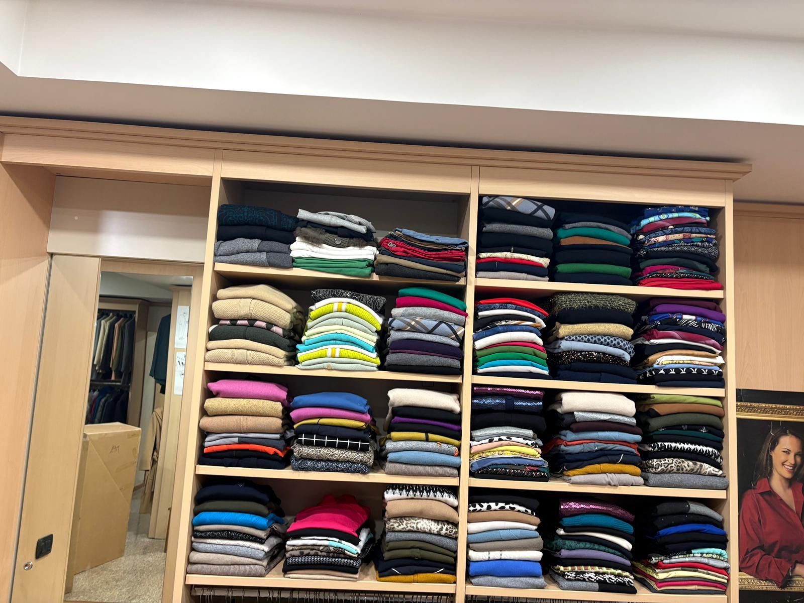 Scaffali pieni di maglioni ordinatamente piegati in vari colori.