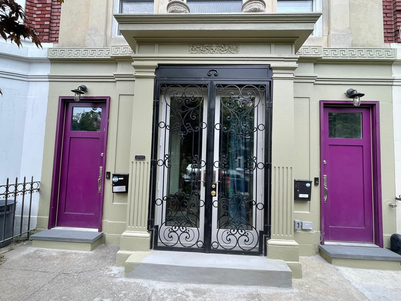 Building entrance with ornate black double doors and two bright purple side doors