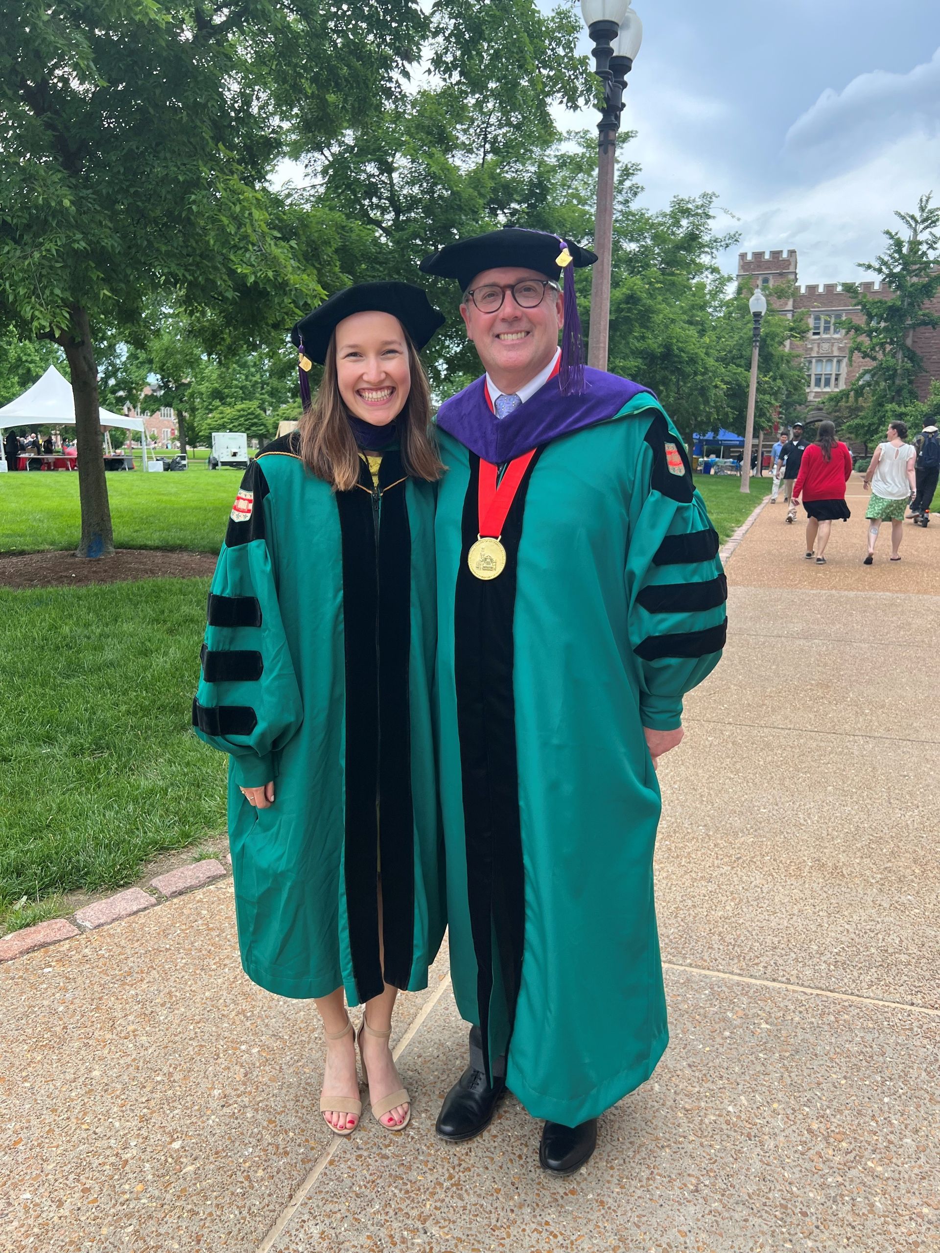 A man and a woman in graduation gowns are posing for a picture.