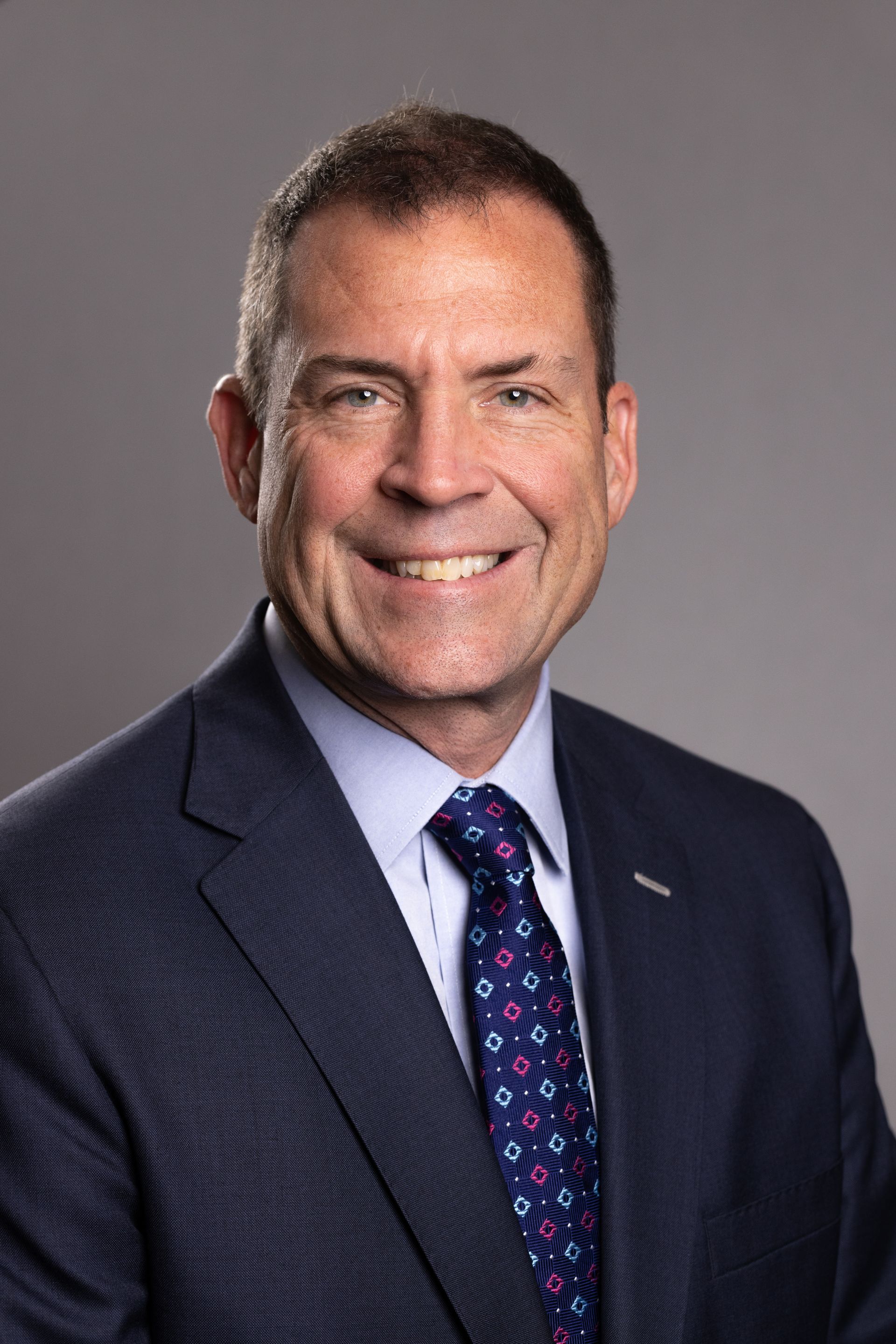 Jim Hansen in a suit and tie is smiling for the camera.