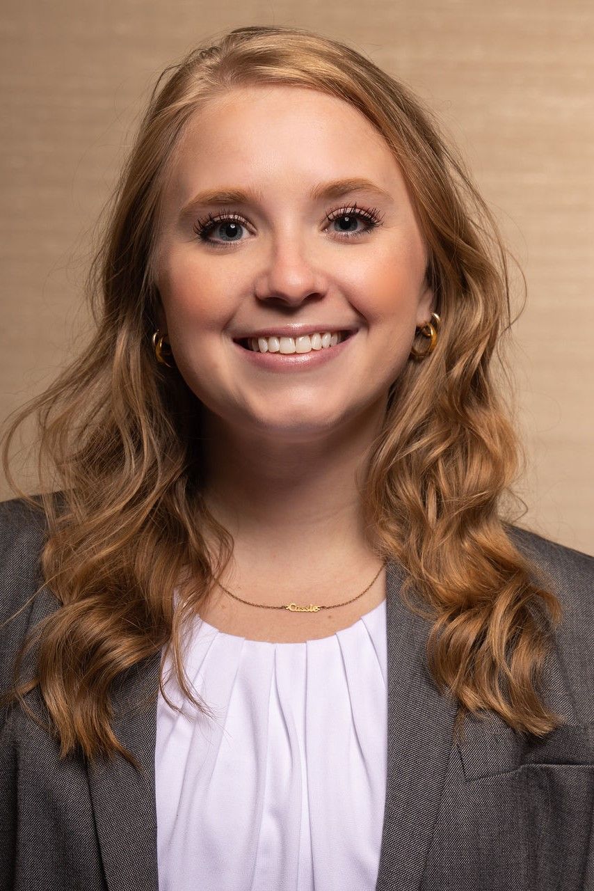 a woman in a suit and white shirt is smiling for the camera .