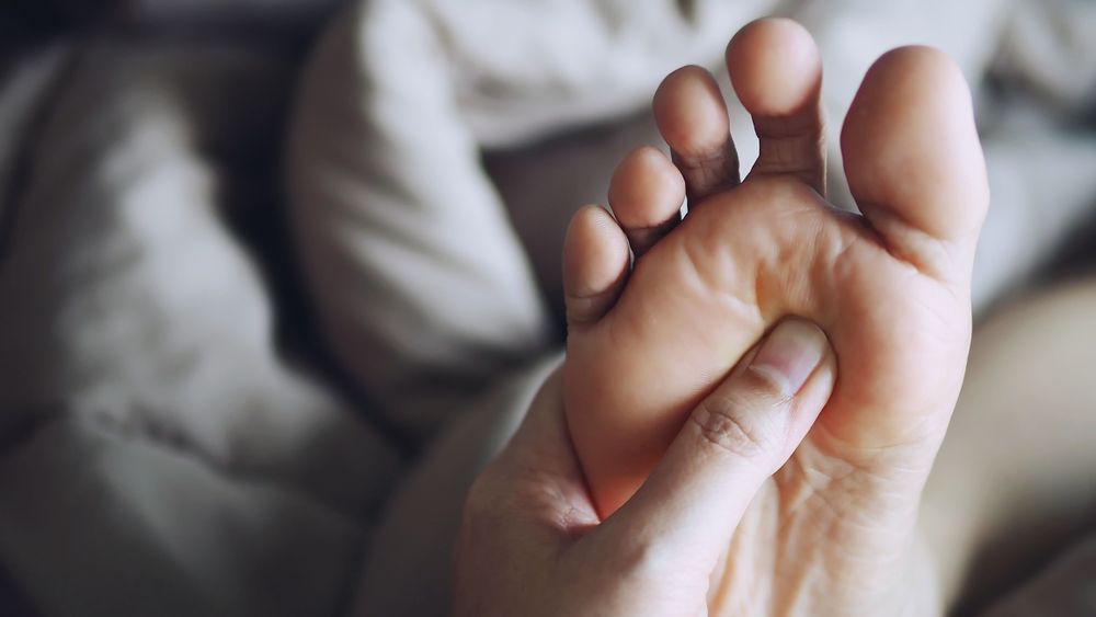 Hand Massaging the Sole of a Foot on a Bed — Leela Thai Massage & Spa in Newtown, QLD
