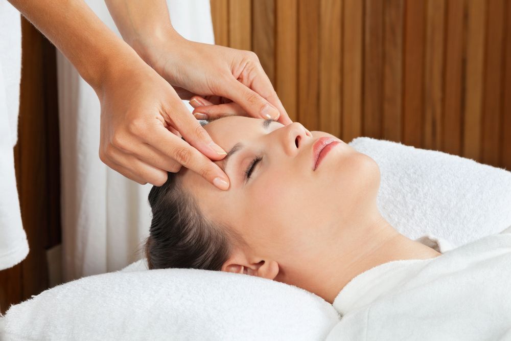 Woman Receiving Facial Massage on a White Towel — Leela Thai Massage & Spa in Newtown, QLD