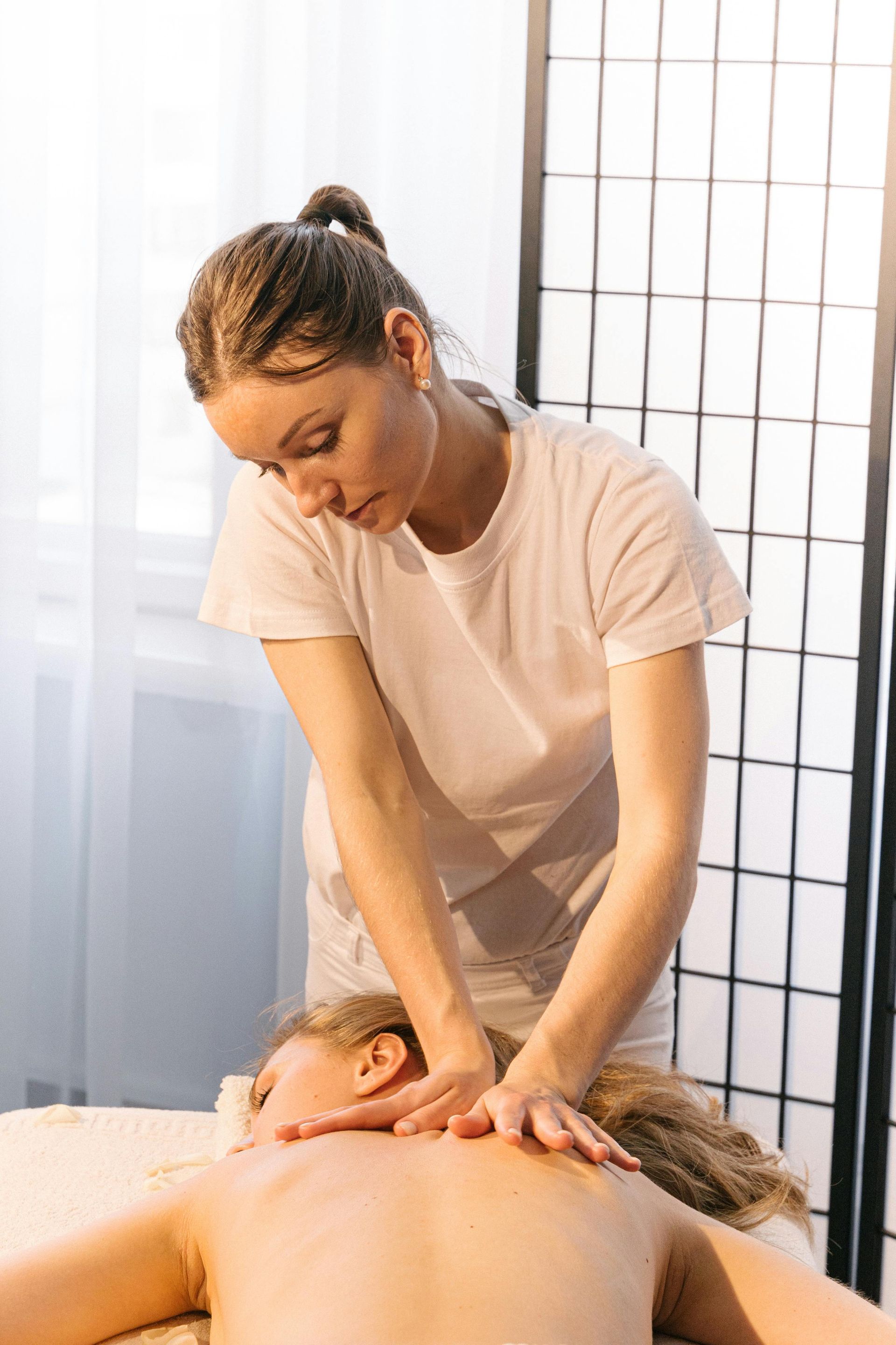 Woman Giving a Back Massage; Both in White Shirts — Leela Thai Massage & Spa in Newtown, QLD