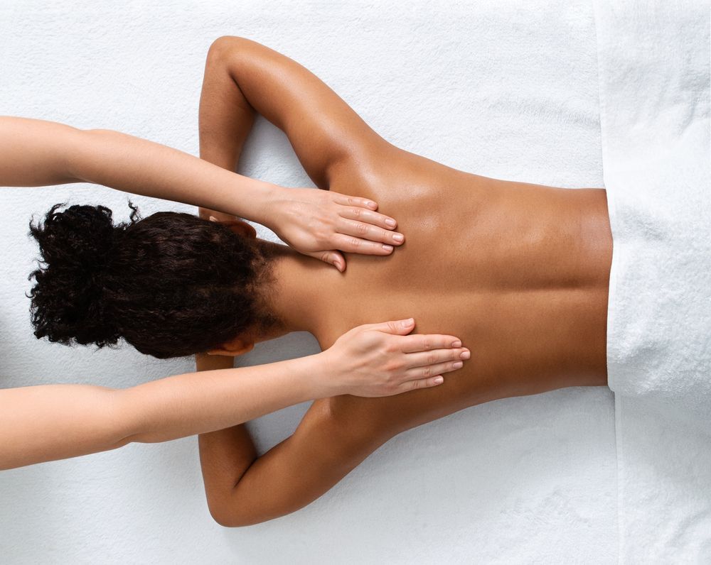 Person Receiving a Back Massage on a White Surface — Leela Thai Massage & Spa in Newtown, QLD