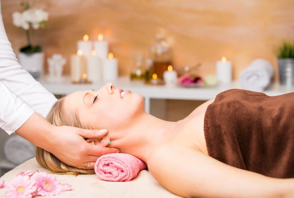 Woman Receiving Neck Massage at a Spa, With Candles, Flowers, and Towels — Leela Thai Massage & Spa in Newtown, QLD