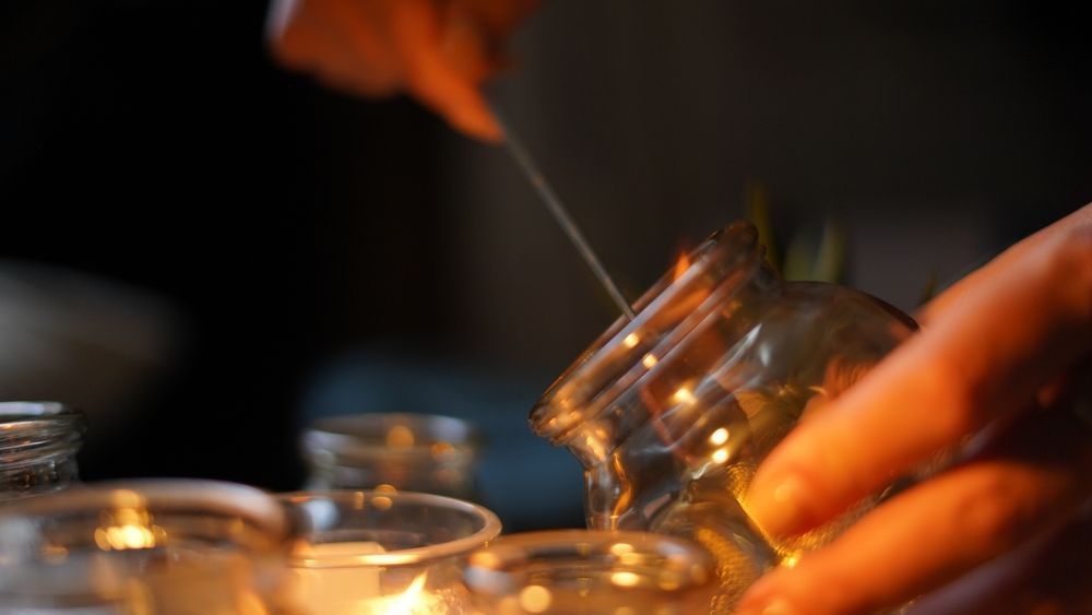 Hands Lighting a Candle in a Glass Jar — Leela Thai Massage & Spa in Newtown, QLD