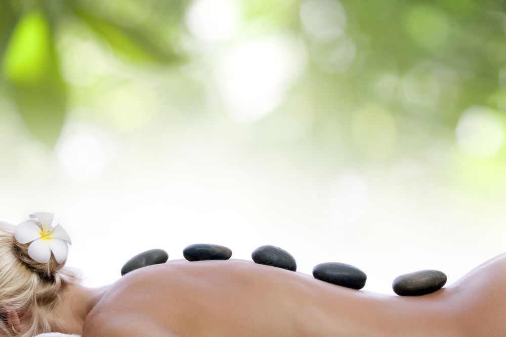 Woman Receiving a Hot Stone Massage Stones Aligned on Her Back — Leela Thai Massage & Spa in Newtown, QLD