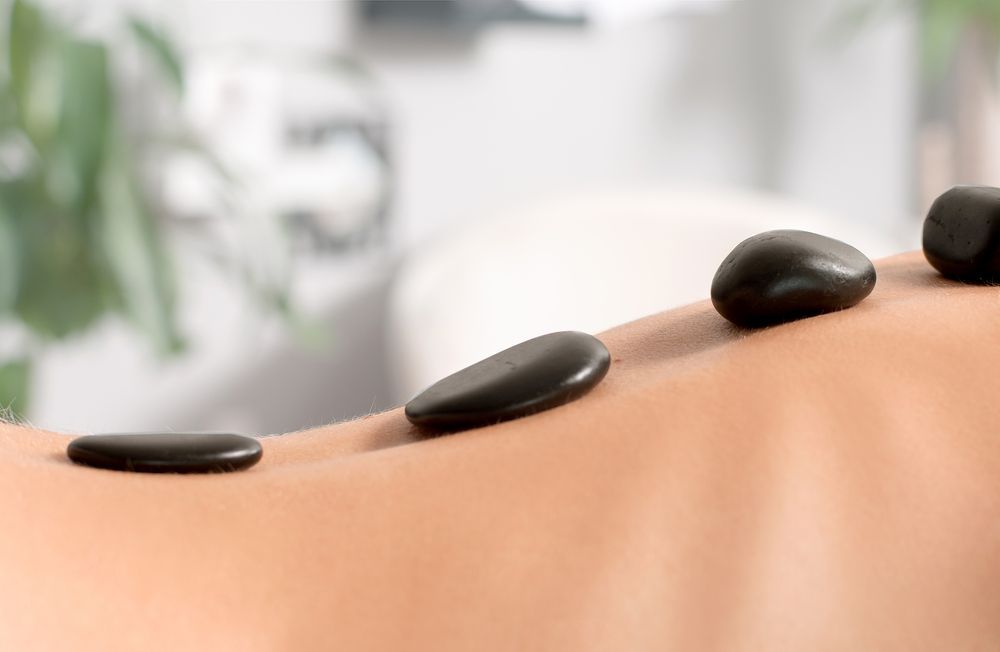 Black Stones on a Person's Back During a Hot Stone Massage — Leela Thai Massage & Spa in Newtown, QLD