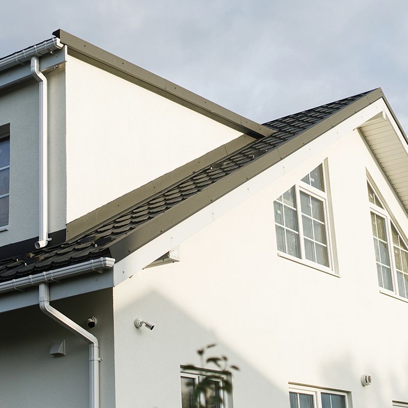 A white house with a black roof and gutters