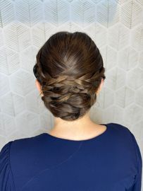 The back of a woman wearing a blue shirt and a bun.
