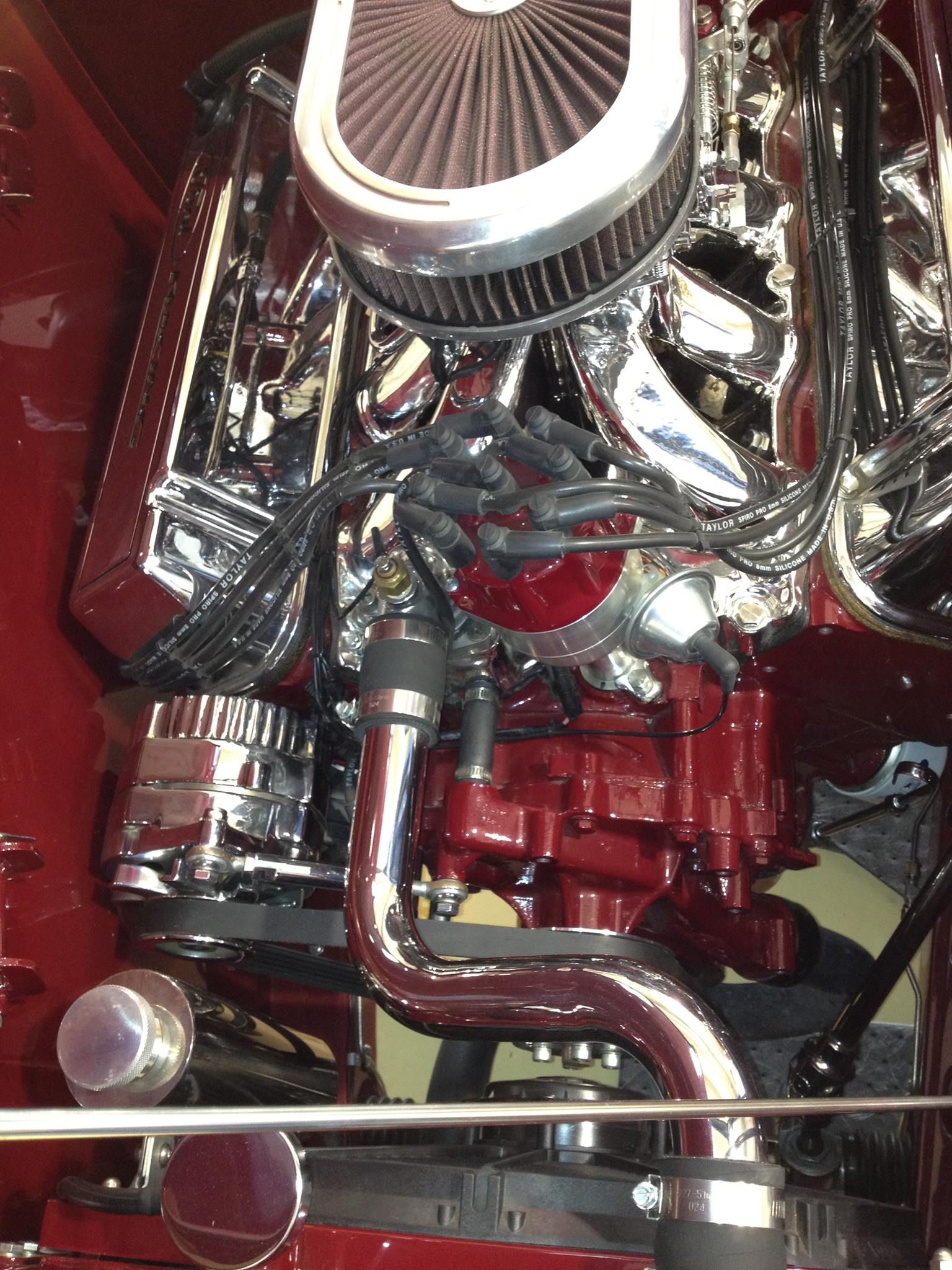 Chrome and red engine with polished air filter and shiny pipes in a car engine bay