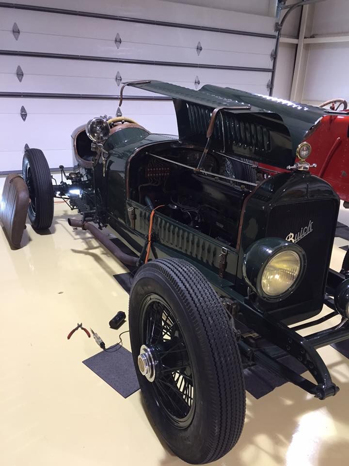 Vintage green open-top race car displayed indoors on a polished floor.