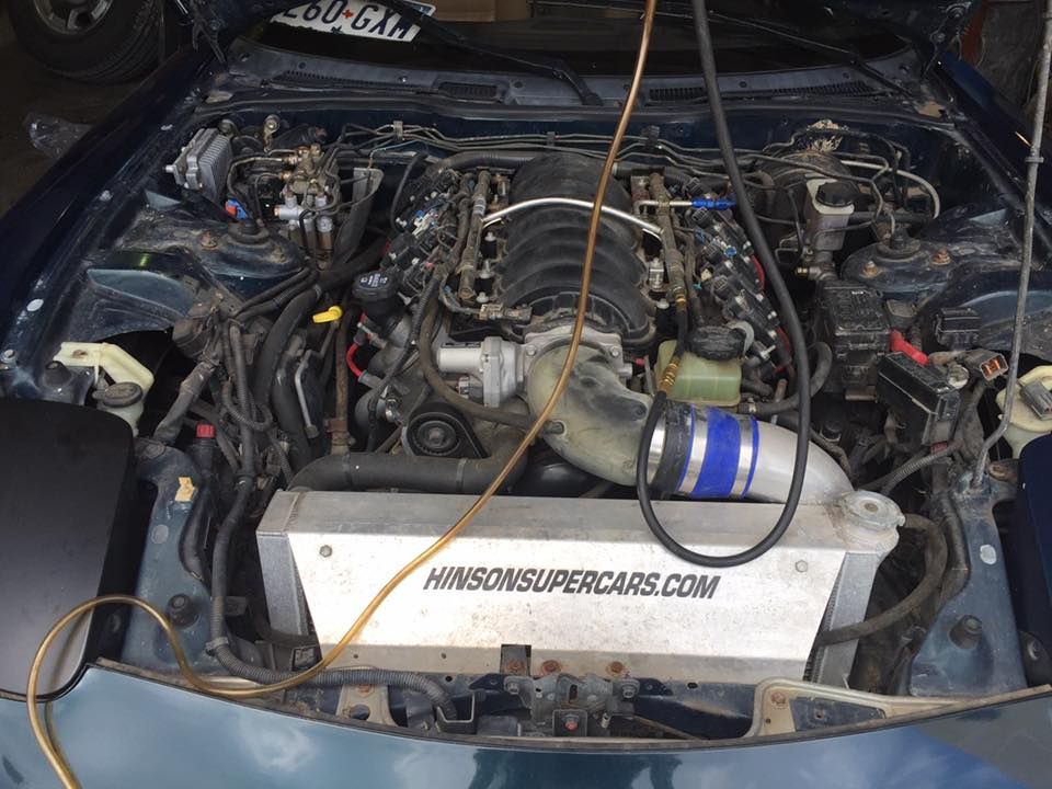 Car engine bay with aftermarket parts and a white radiator cover labeled “HONDASUPERPERCARS.COM”