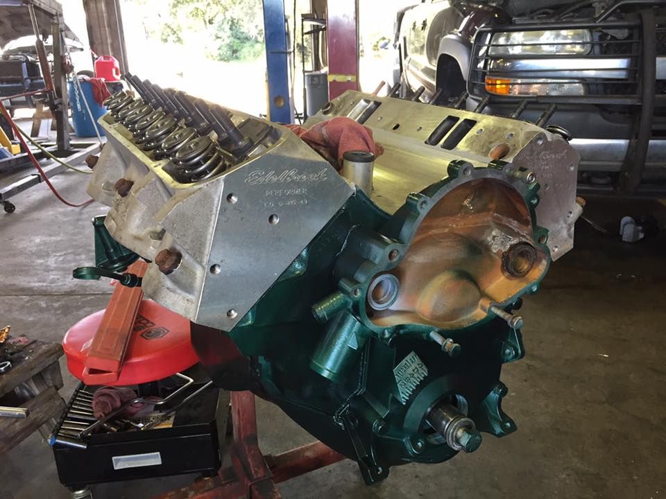 Large V8 engine block on a workshop floor, with red and green components and exposed cylinder heads