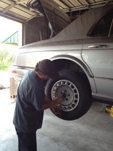 Mechanic tightening a wheel lug nut on a silver car inside a garage