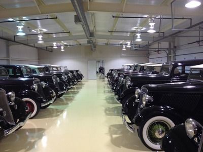 Rows of black vintage cars displayed in a bright indoor showroom