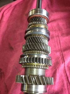 Stacked metal gears and shafts on a pink background
