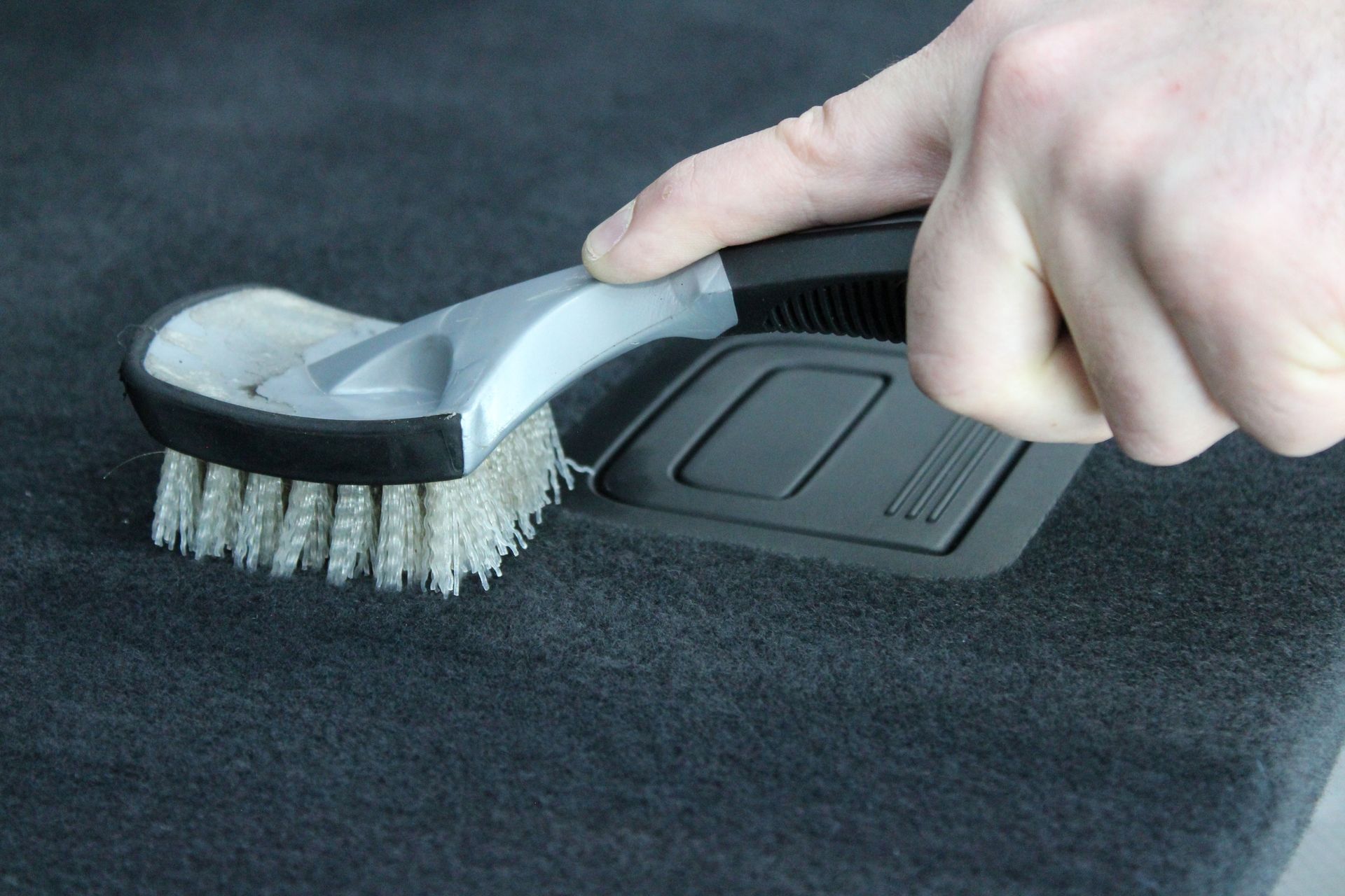 A person is cleaning the dashboard of a car with a cloth.