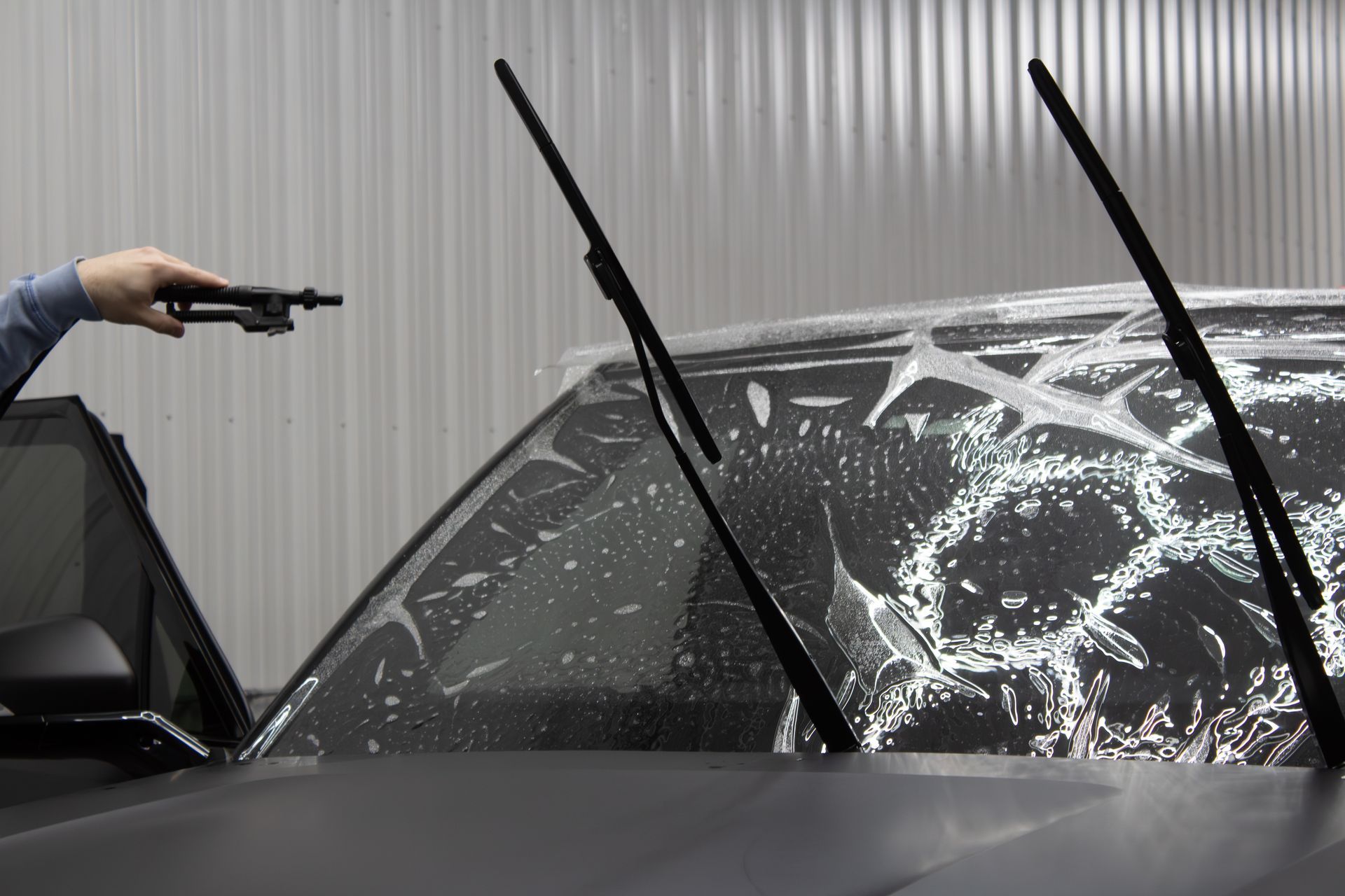 A person is applying protective film to the hood of a car.