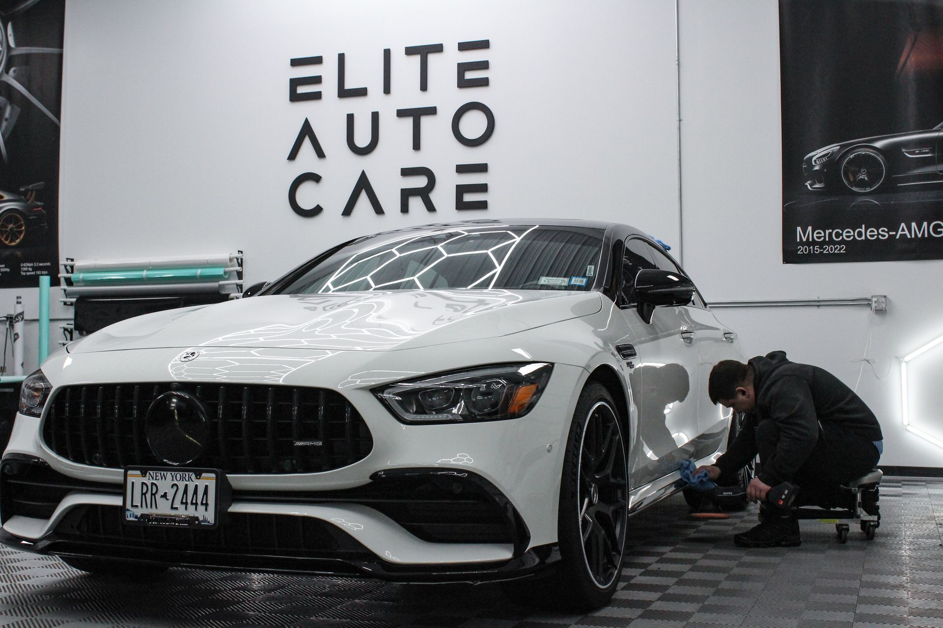 A man is polishing the hood of a car with a machine.