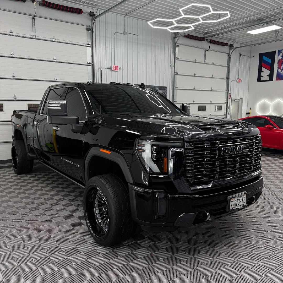 Black GMC truck parked inside a garage, next to a red car.