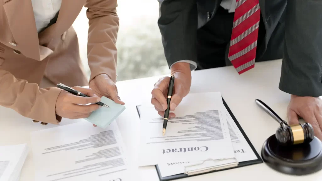 Business professionals reviewing and signing a contract with a legal gavel on the table.