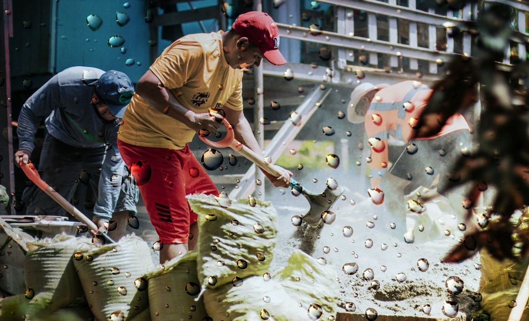 Men filling sandbags outdoors to prevent flooding.