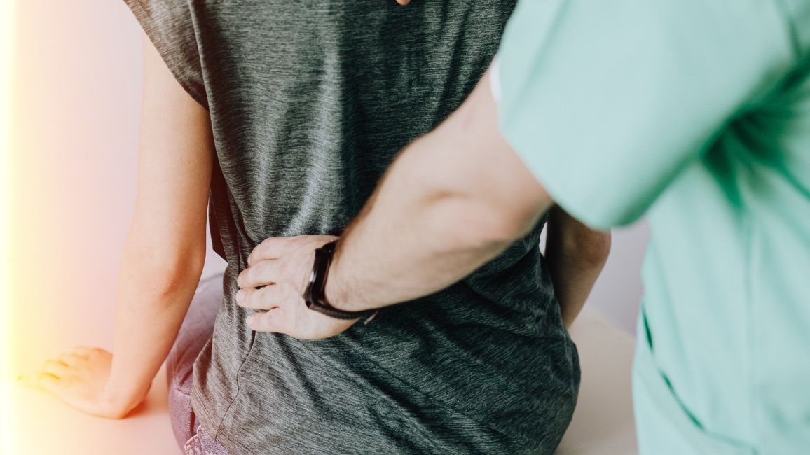 Person with back pain being examined by a healthcare provider.