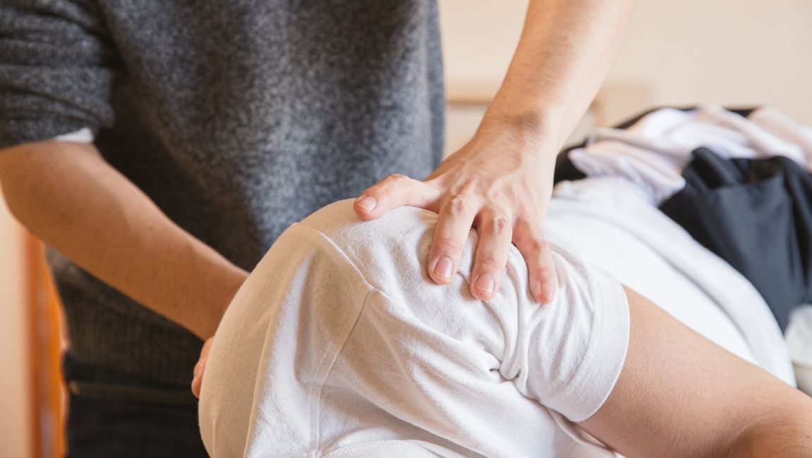 Person's shoulder being examined by another person's hands; hands are on the shoulder.