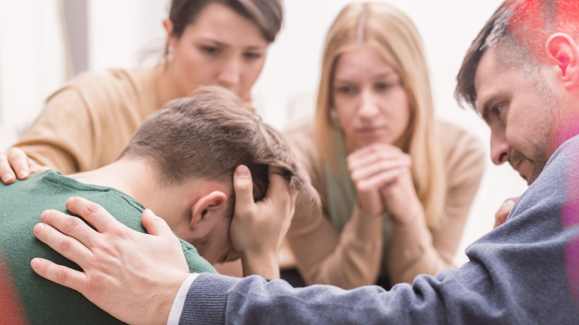 Group of people comforting a person with head in hands, indoors.