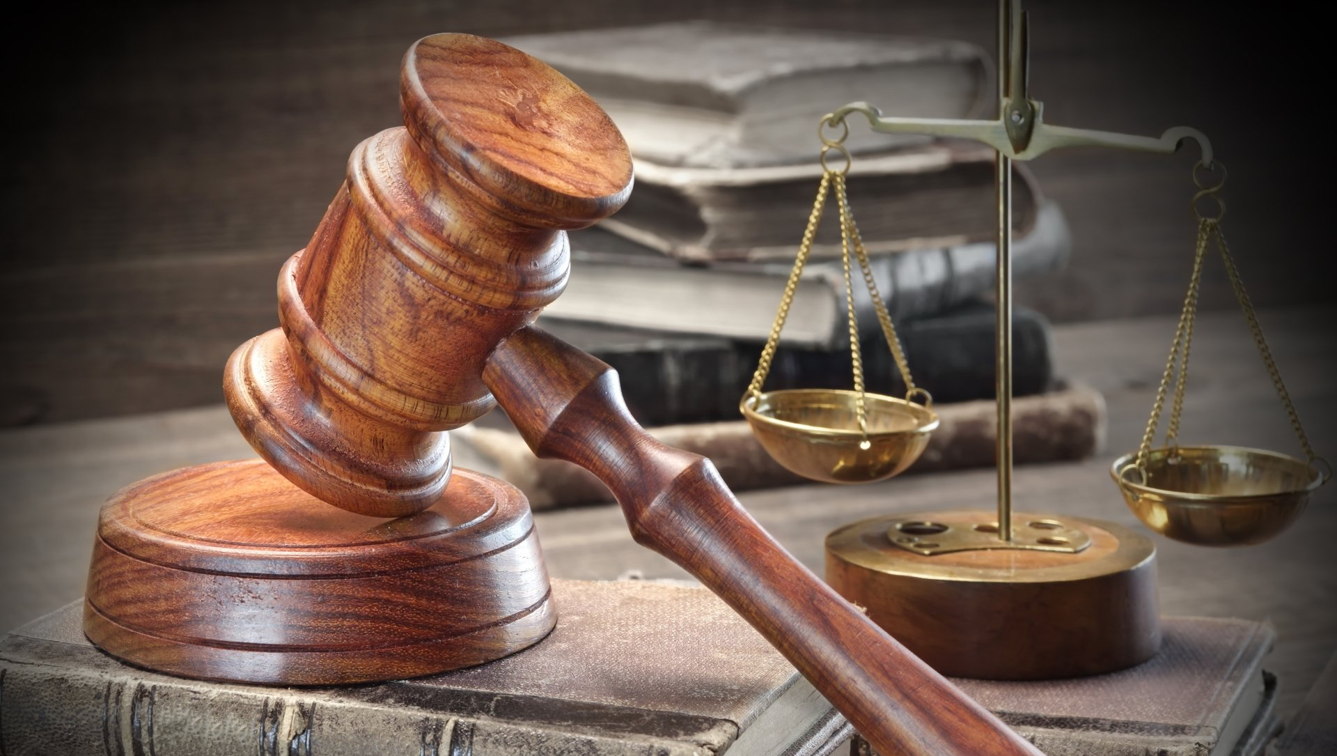 Wooden gavel and scales of justice on a stack of law books.