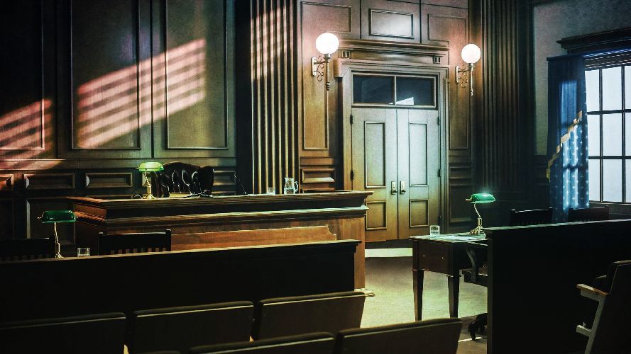 Empty courtroom with wooden paneling, a judge's bench, and rows of seats. Sunlight through a window.