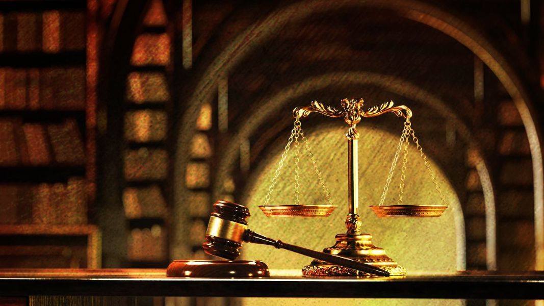 Gavel and scales of justice on a table in a library with books.
