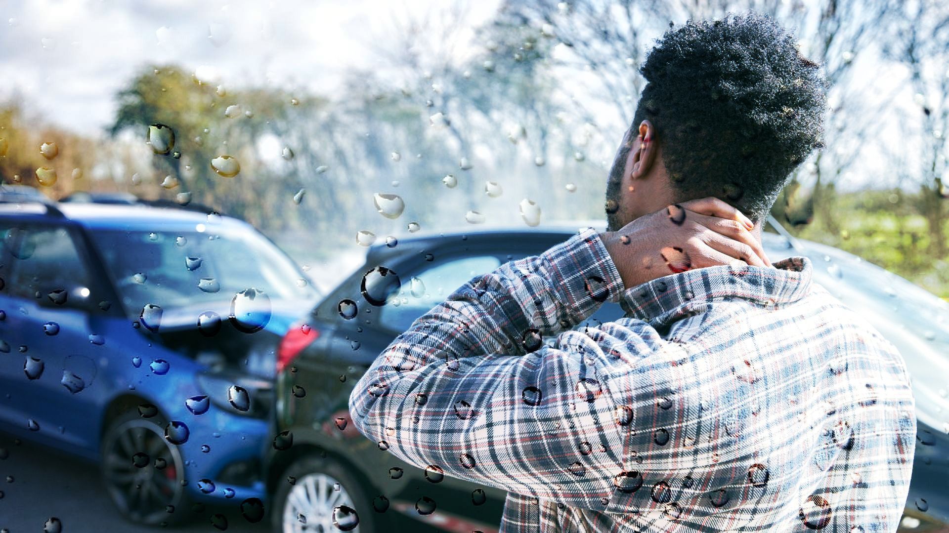 Man holding neck, looking at car accident with damaged vehicles.