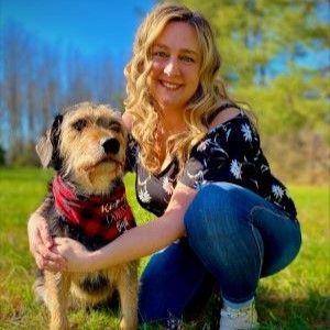 a woman is kneeling down next to a dog in a field .