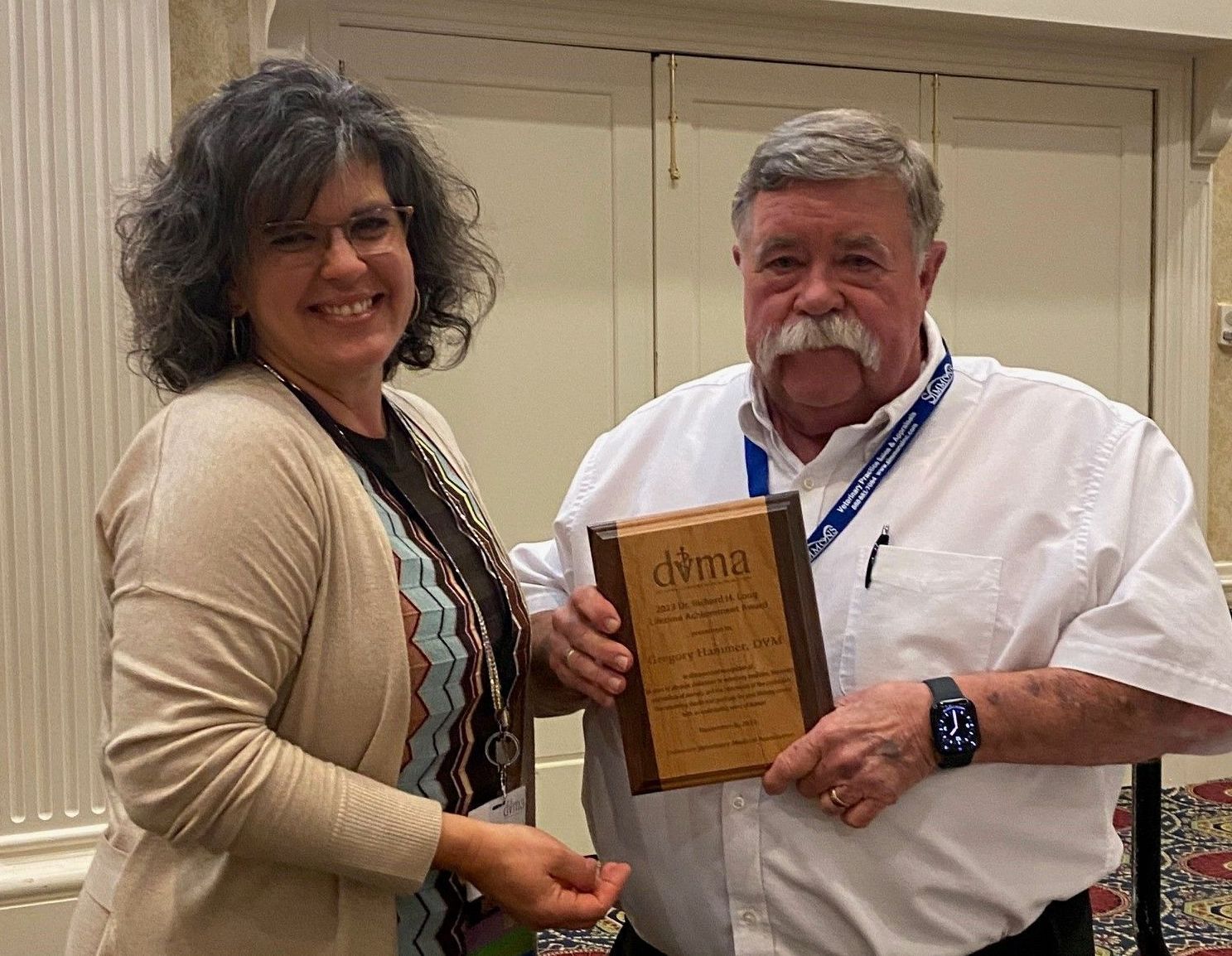 a man and a woman are standing next to each other holding a plaque .