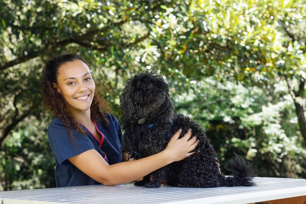 a woman is petting a black dog on a table .