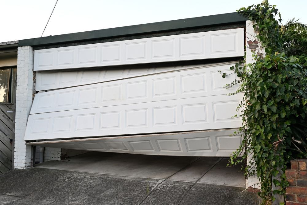 Partially open white garage door, tilted downward with a vine-covered wall beside it