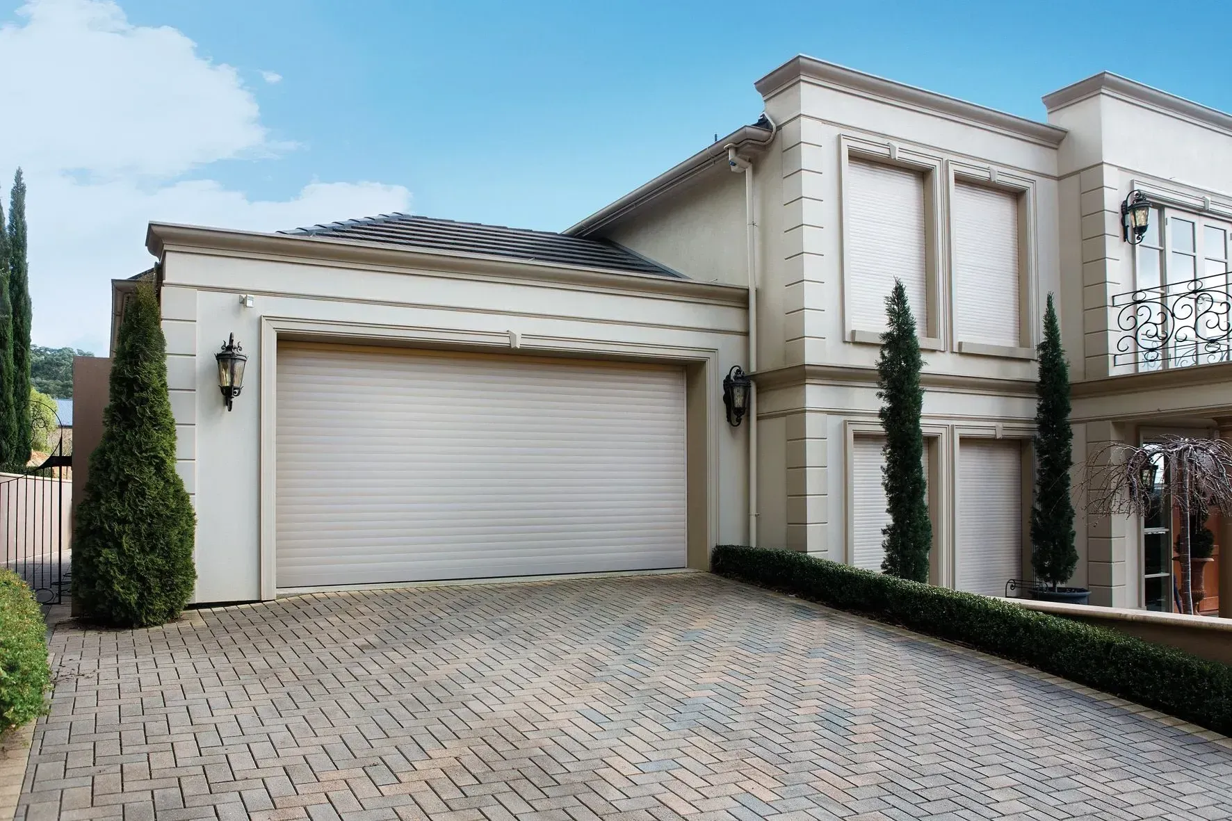 Beige stucco house with a brick driveway and garage.