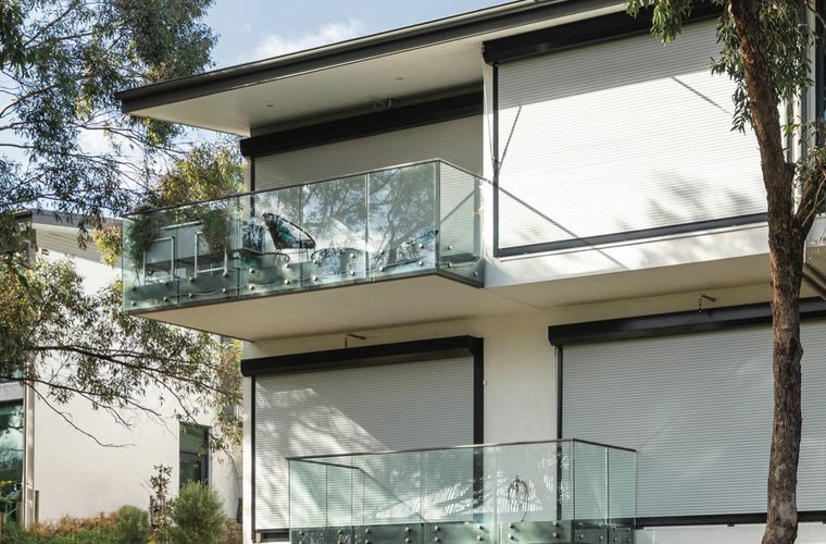 Modern house with balconies, glass railings, and retractable sun shades.