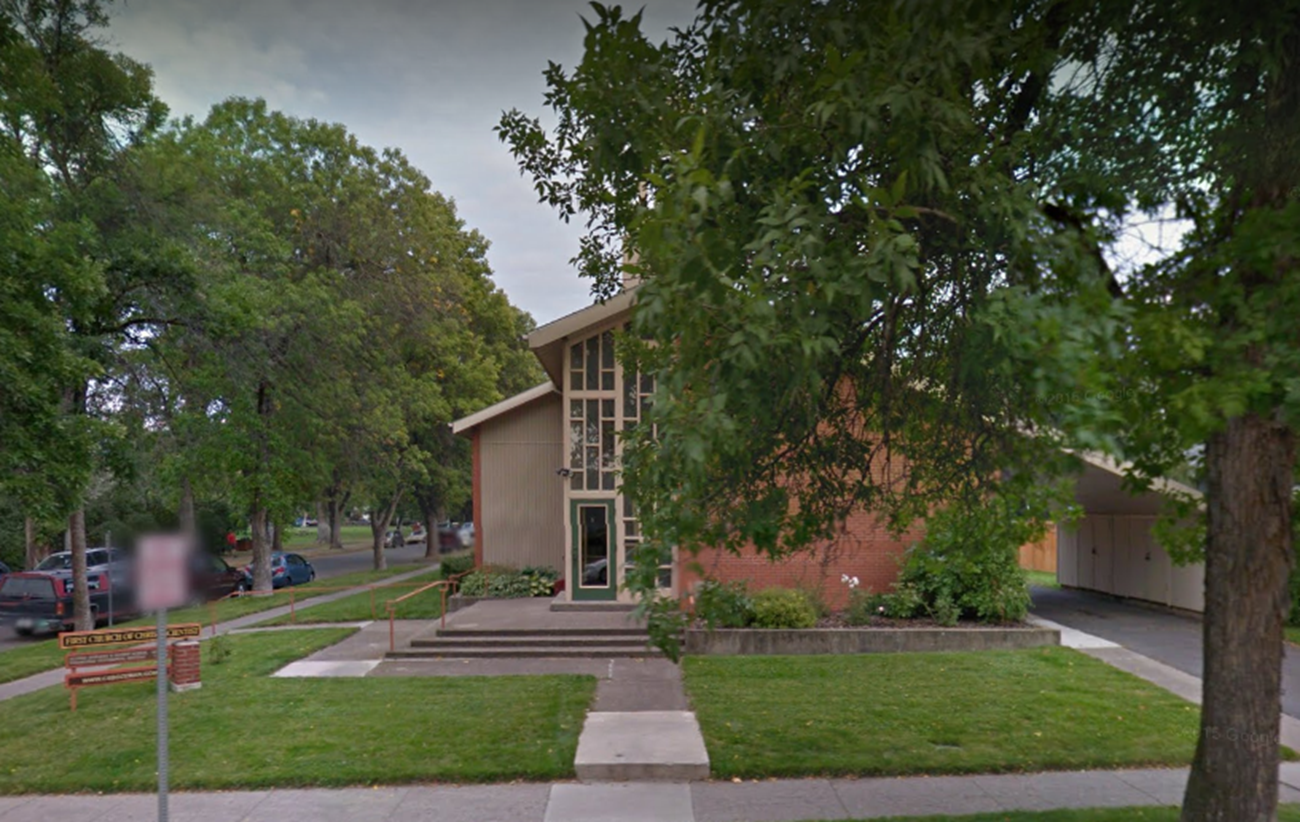 Suburban house with front lawn, large tree, sidewalk, and driveway on a quiet street