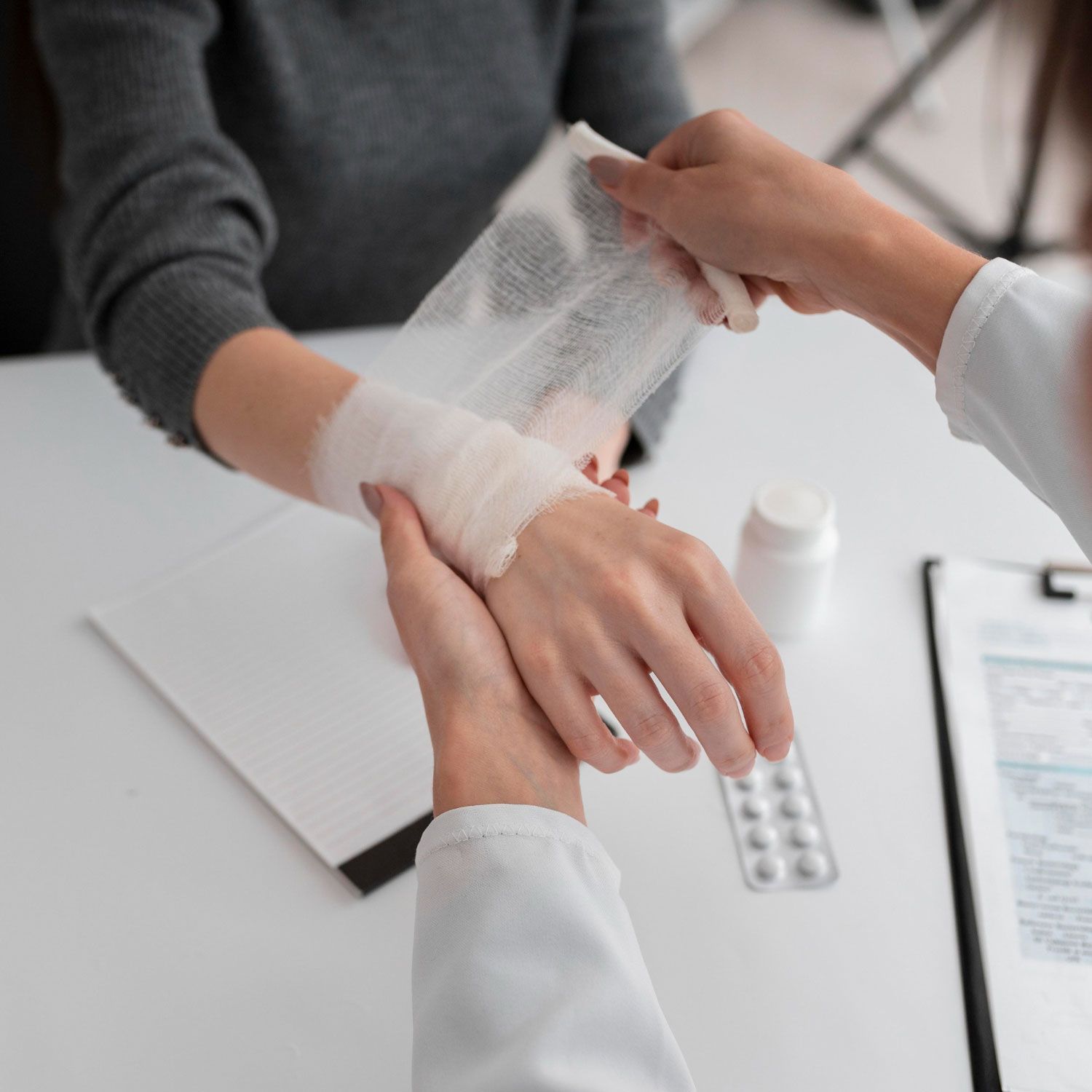 A woman is getting a bandage on her wrist by a doctor.