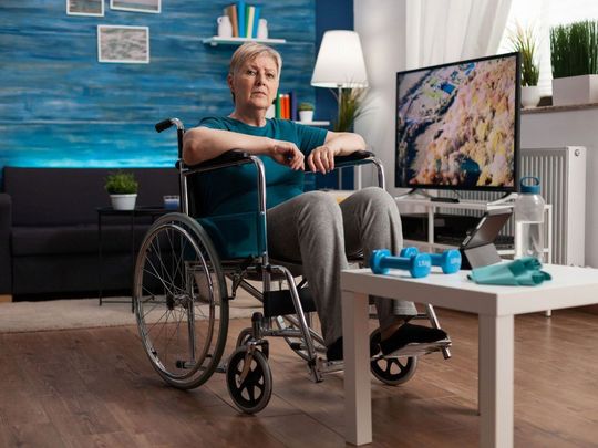 An elderly woman in a wheelchair is sitting in a living room.