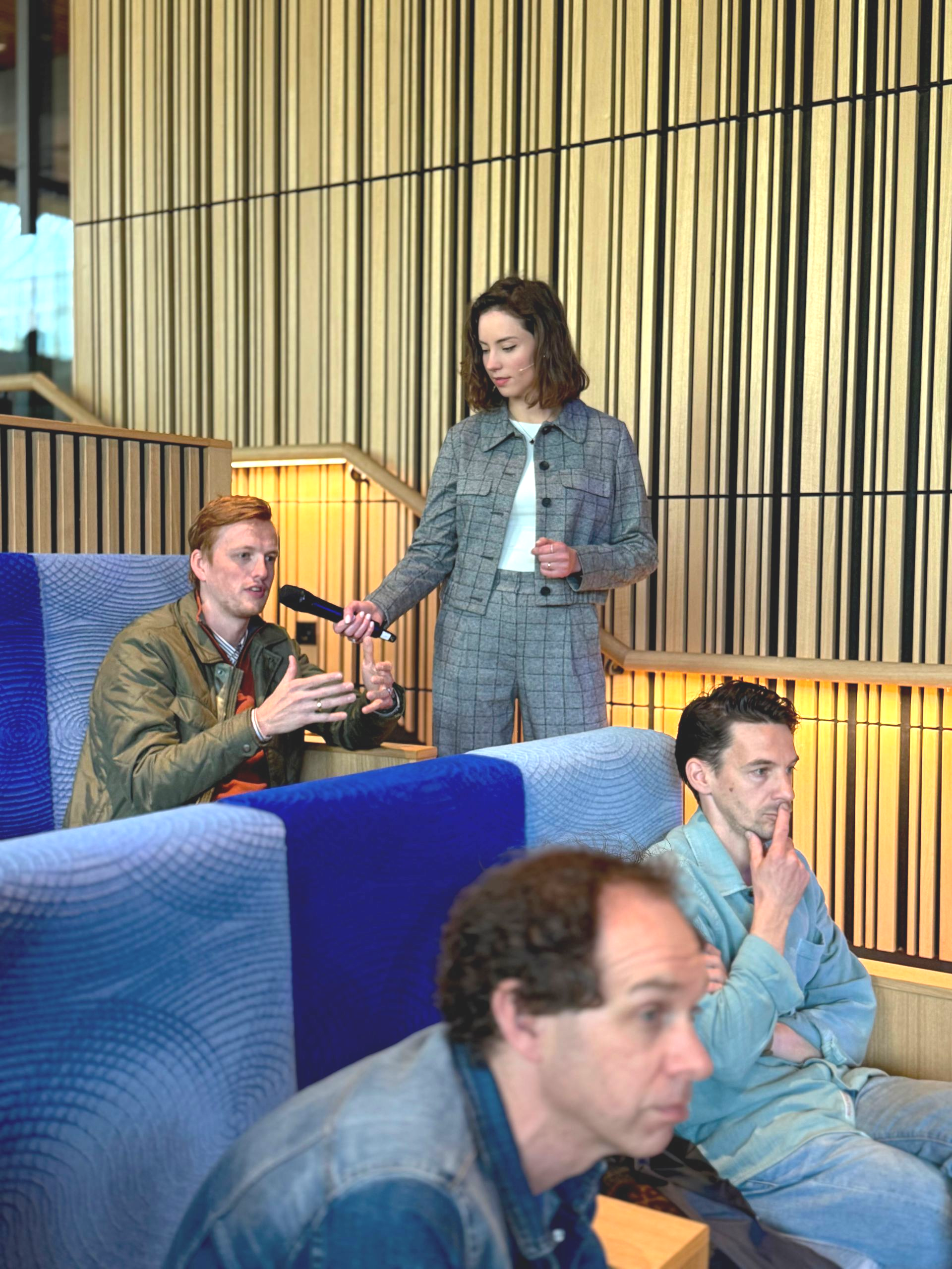 Vrouw interviewt een man in het publiek in een zakelijke zaal.