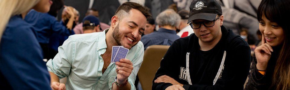 young looks at cards and smiles next to his friends.