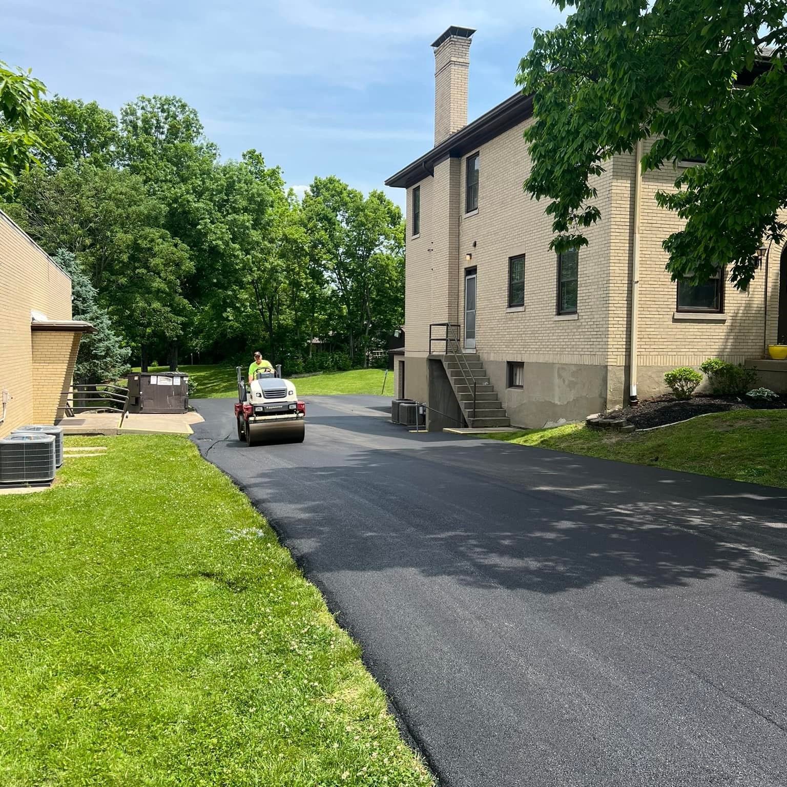 A car is driving down a driveway next to a house.